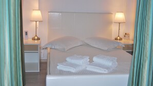 A neatly made bed with pillows and folded towels, bedside lamps, and a small bedside table. - Casa Mendeleev (Bucharest)