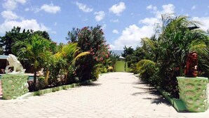 Un sendero pavimentado bordeado de abundante vegetación y estatuas decorativas.