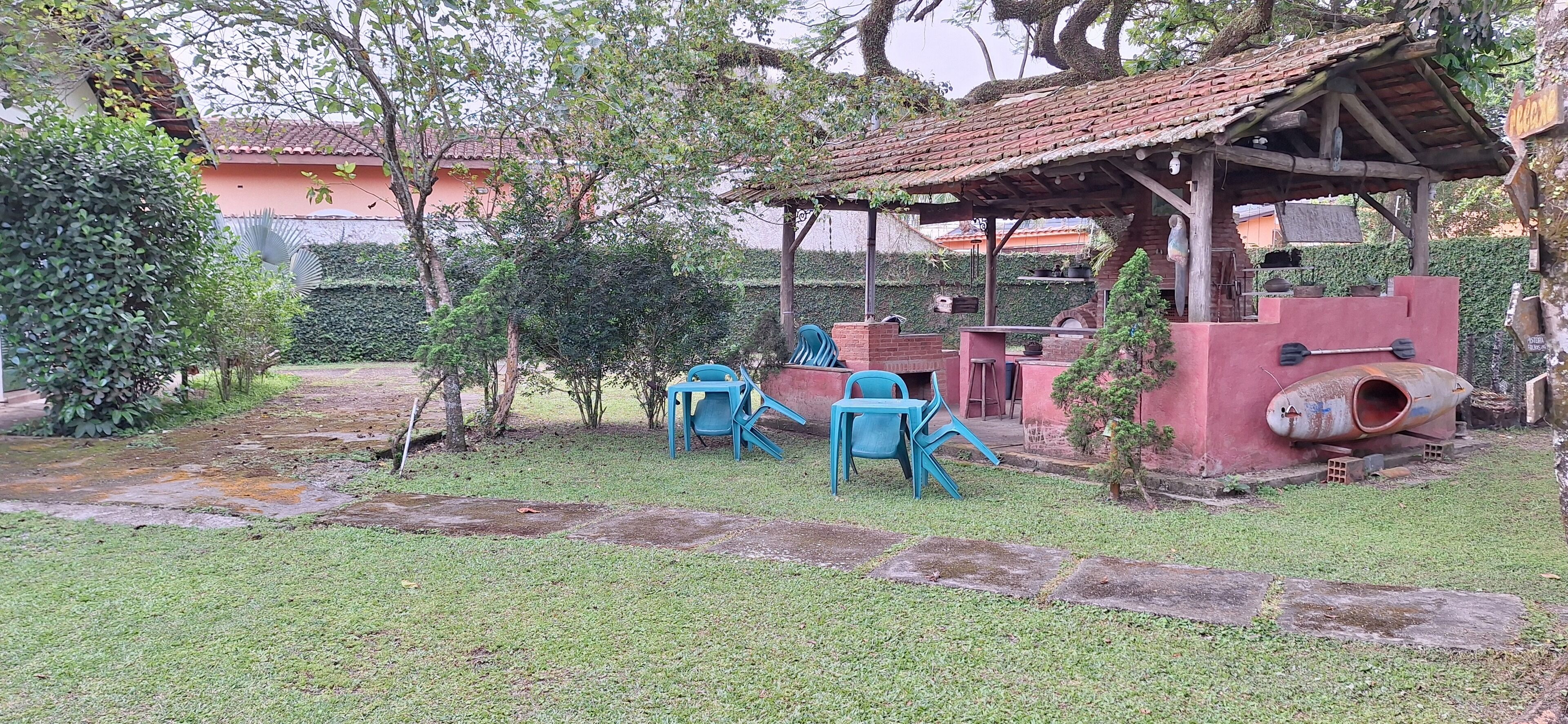 A rustic outdoor seating area with a brick structure, stone pathway, and greenery.