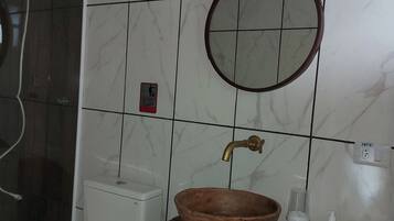 Une salle de bain avec des toilettes blanches, un lavabo en bois, un miroir rond et un porte-serviettes.