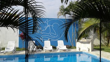 Relax by the serene pool surrounded by lounge chairs and shaded by palm trees.