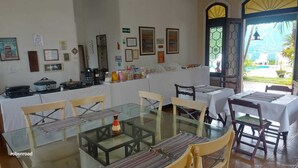 Un comedor con mesas y sillas de vidrio, un bufé y vista a una piscina a través de un ventanal.