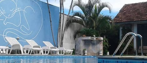 Una piscina al aire libre, sombrillas, sillones reclinables de piscina