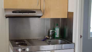 A compact kitchen with a built-in stove, a sink, and a cabinet above.