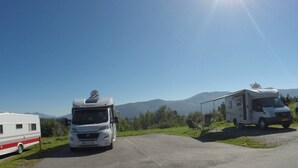 Un área de estacionamiento con vehículos recreativos y una caravana.