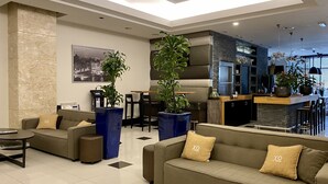 A modern living area with sofas, a dining table, and potted plants. - XO Hotels Blue Tower (Amsterdam)