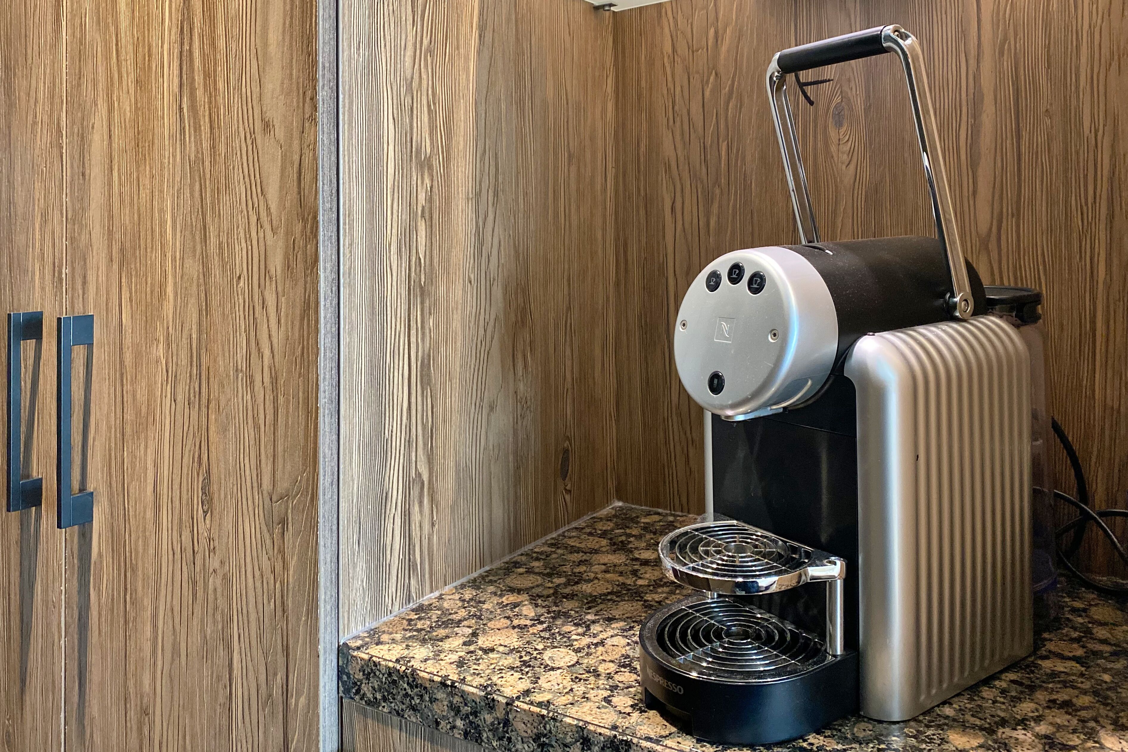 Une machine à expresso portative posée sur un plan de travail en granit, dans une pièce aux murs lambrés.