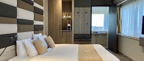 Une chambre d’hôtel moderne avec un grand lit, une armoire en bois, une petite salle de bain et une vue sur la ville.