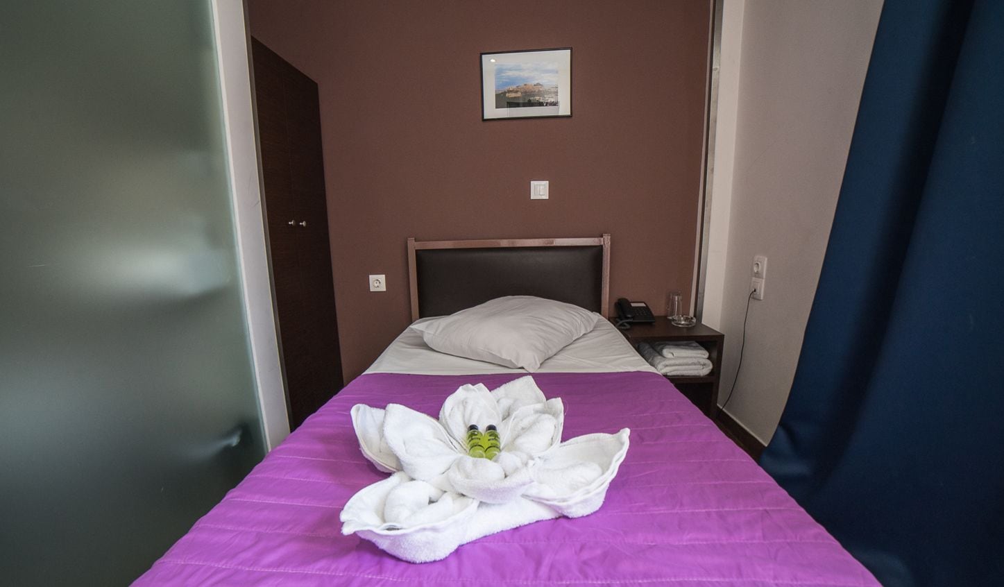 Ein Hotelzimmer mit Bett, Nachttisch, einem Bild an der Wand und einer violetten Bettdecke.