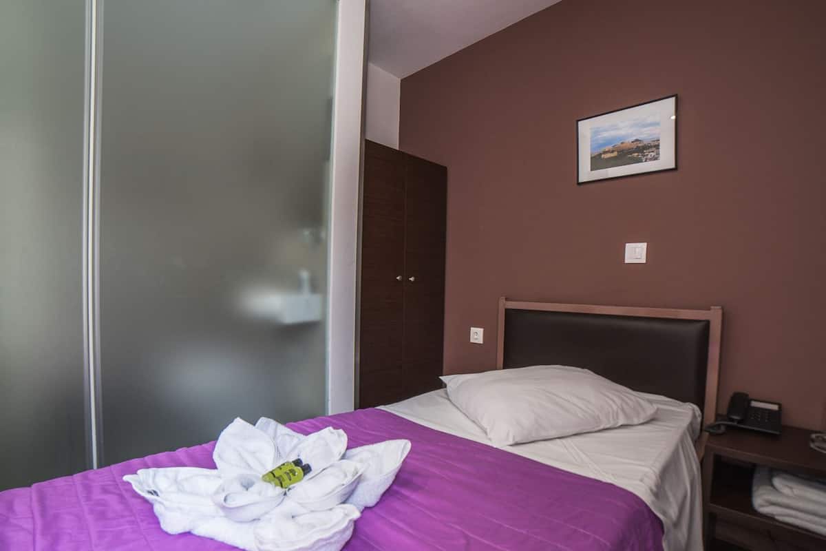 Habitación de hotel con cama, mesita de noche, un cuadro en la pared y una puerta corredera.