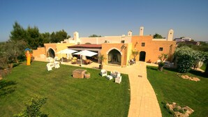 A spacious outdoor patio with a paved walkway, surrounded by well-maintained grass and potted plants.