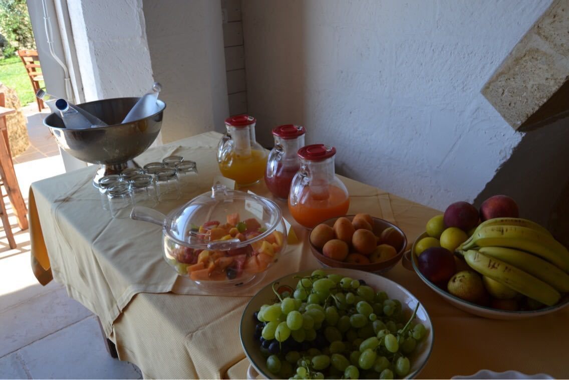 A table with various food items including fruits, a bowl of grapes, and juice bottles.