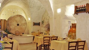 A restaurant with round tables, chairs, and a large stone wall.