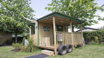 A small wooden building with a porch, a sign reading "LAST STOP GASOLINE," and two large tires attached to the side.