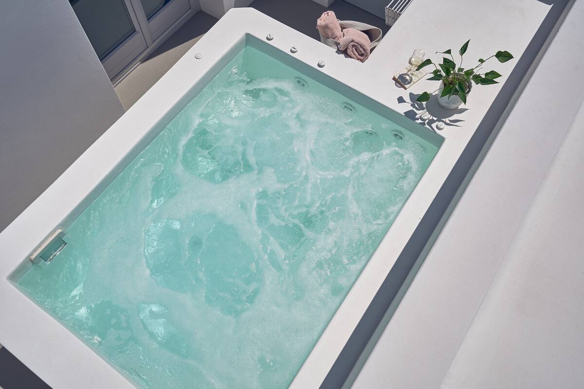 Tinaja rectangular con superficie de agua azul cristalina, una toalla y una planta en maceta en el borde.