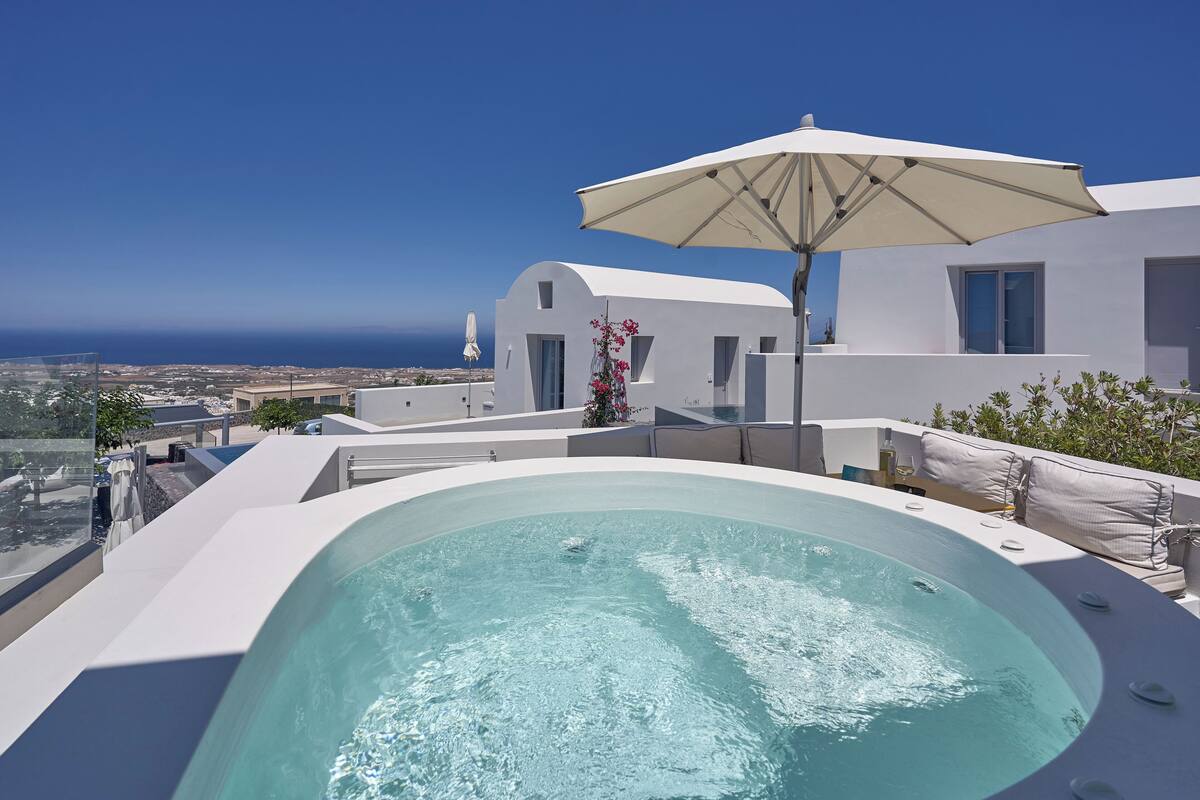 Un hotel moderno con piscina infinita en la azotea, arquitectura blanca y vistas al océano.
