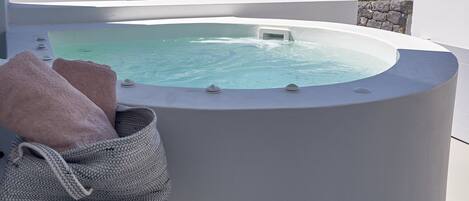 A modern outdoor hot tub with a clear view of the landscape in the background.