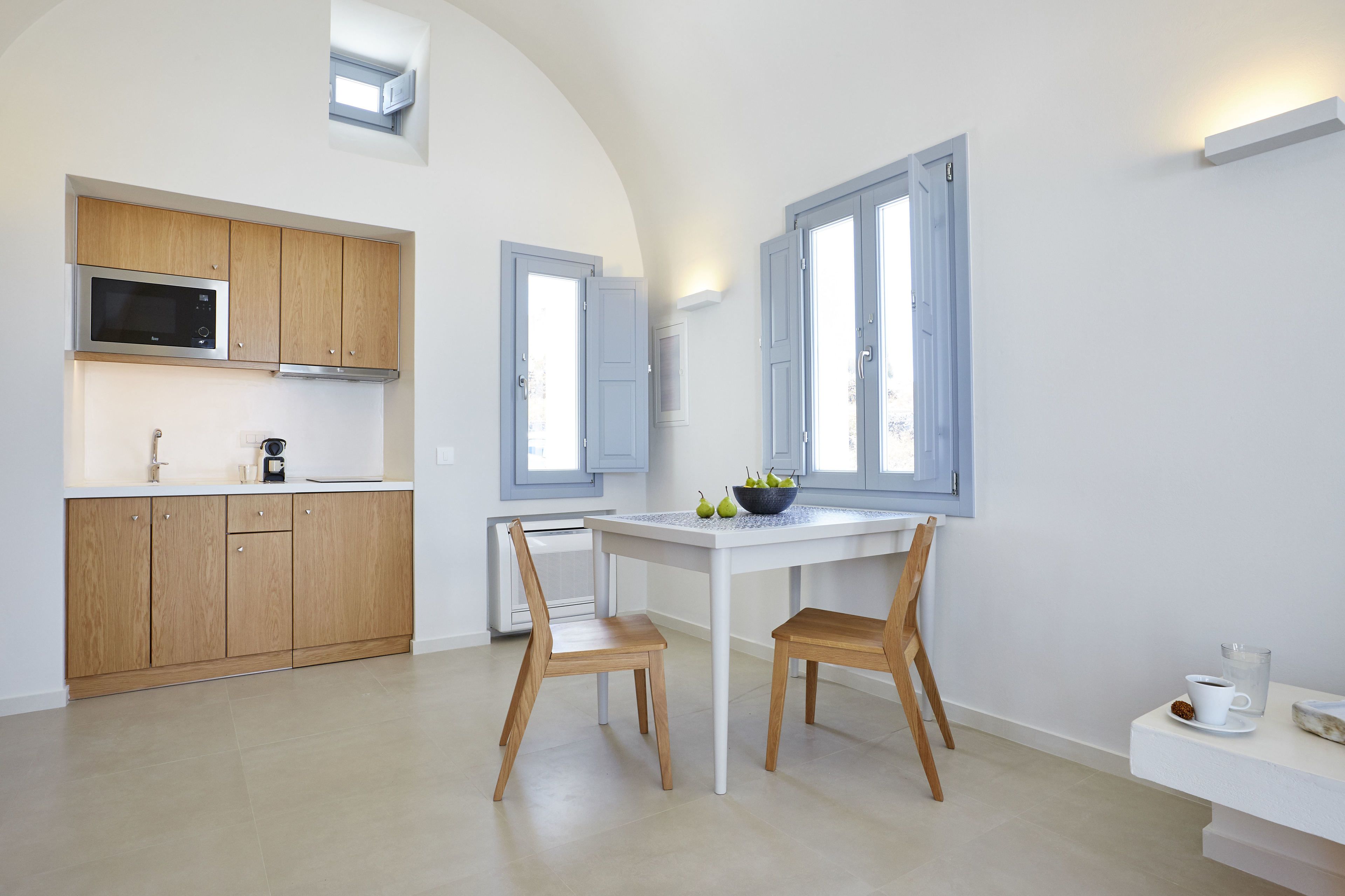 Una cocina moderna con armarios de madera, una mesa de comedor blanca y dos sillas.