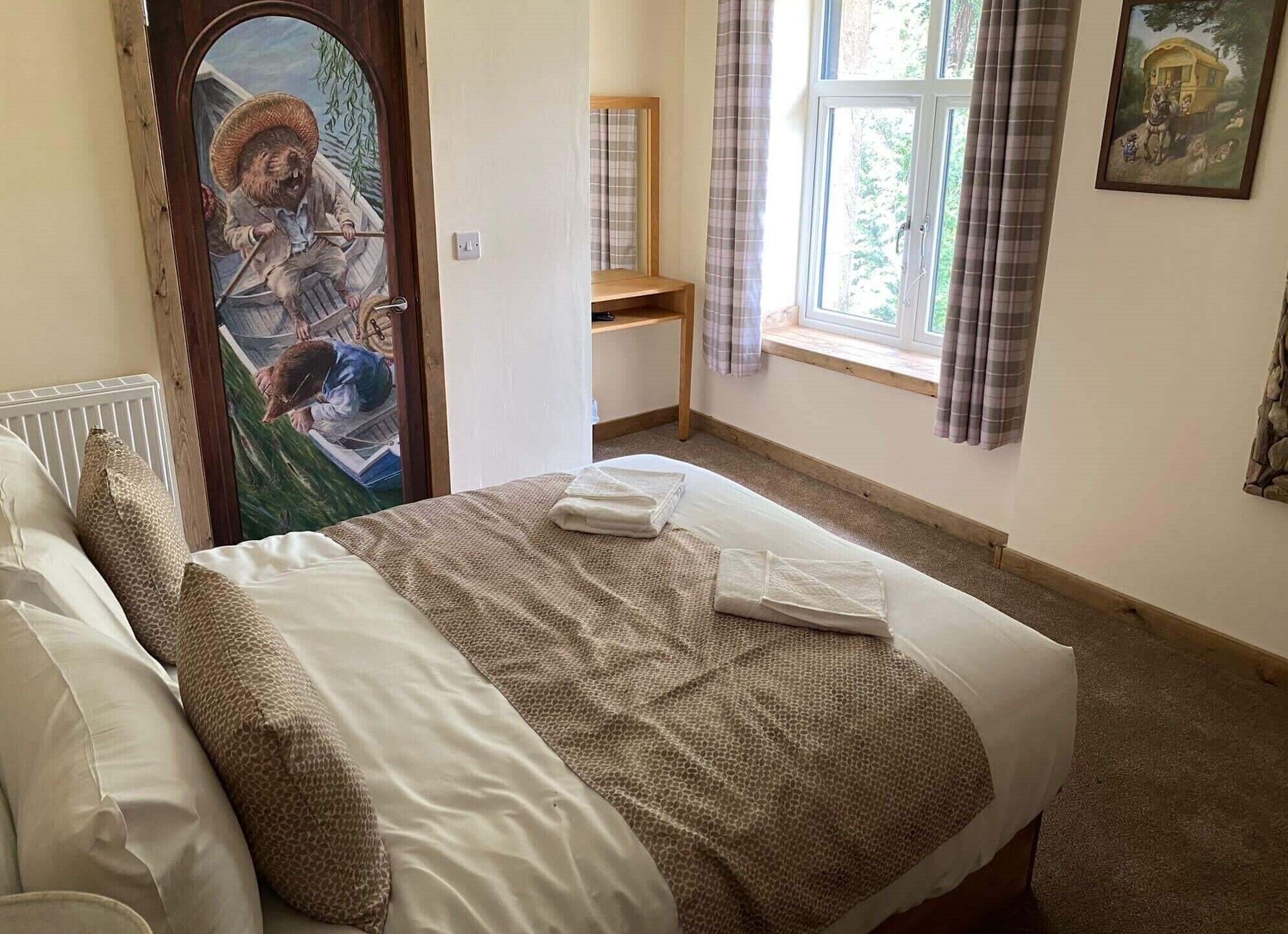 A bedroom with a bed, a radiator, a window with curtains, and a painting on the wall.