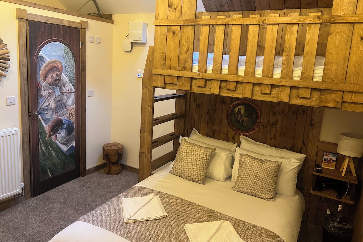 A cozy room with a bed, wooden headboard, and a mural on the door.