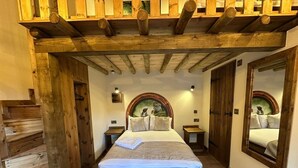 Une chambre avec un escalier en bois, un lit doté d’une tête de lit et un miroir au mur.