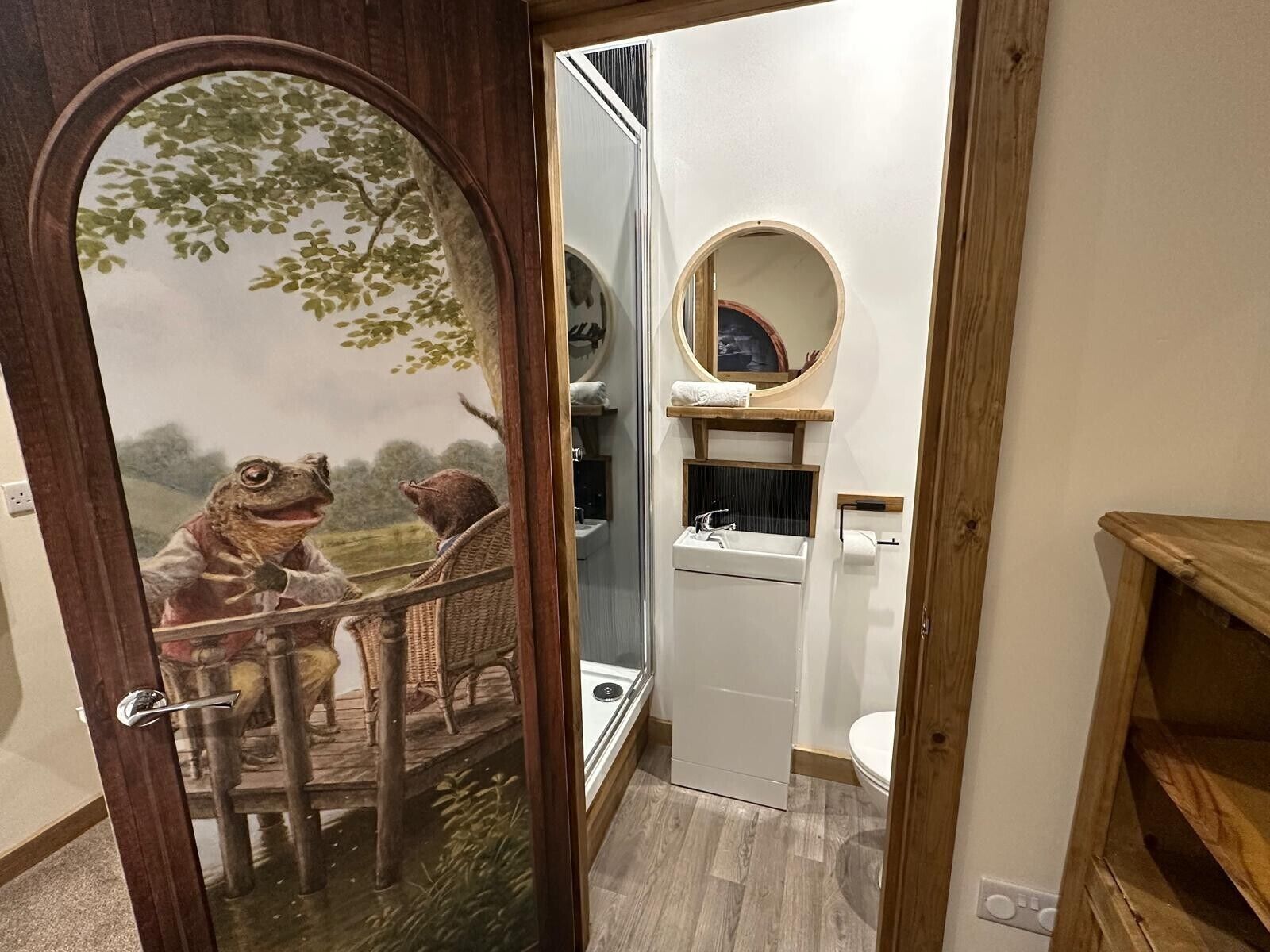 A bathroom with a wooden door, a white sink, a mirror, and a toilet.