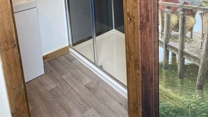 Une salle de bain moderne avec une douche à parois de verre, un plancher en bois et un cadre en bois rustique orné d'une peinture représentant une grenouille.