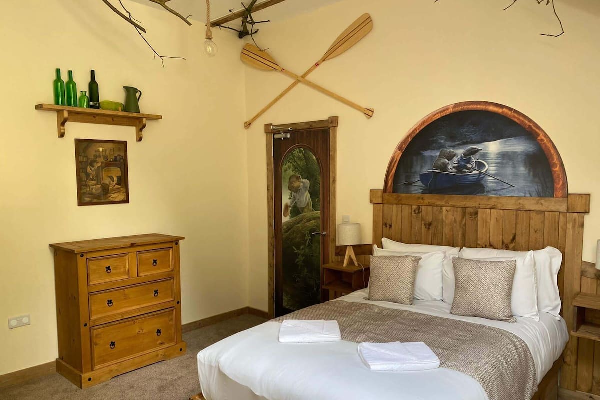 A bedroom with a wooden bed, a nightstand, a dresser, and a painting above the bed.