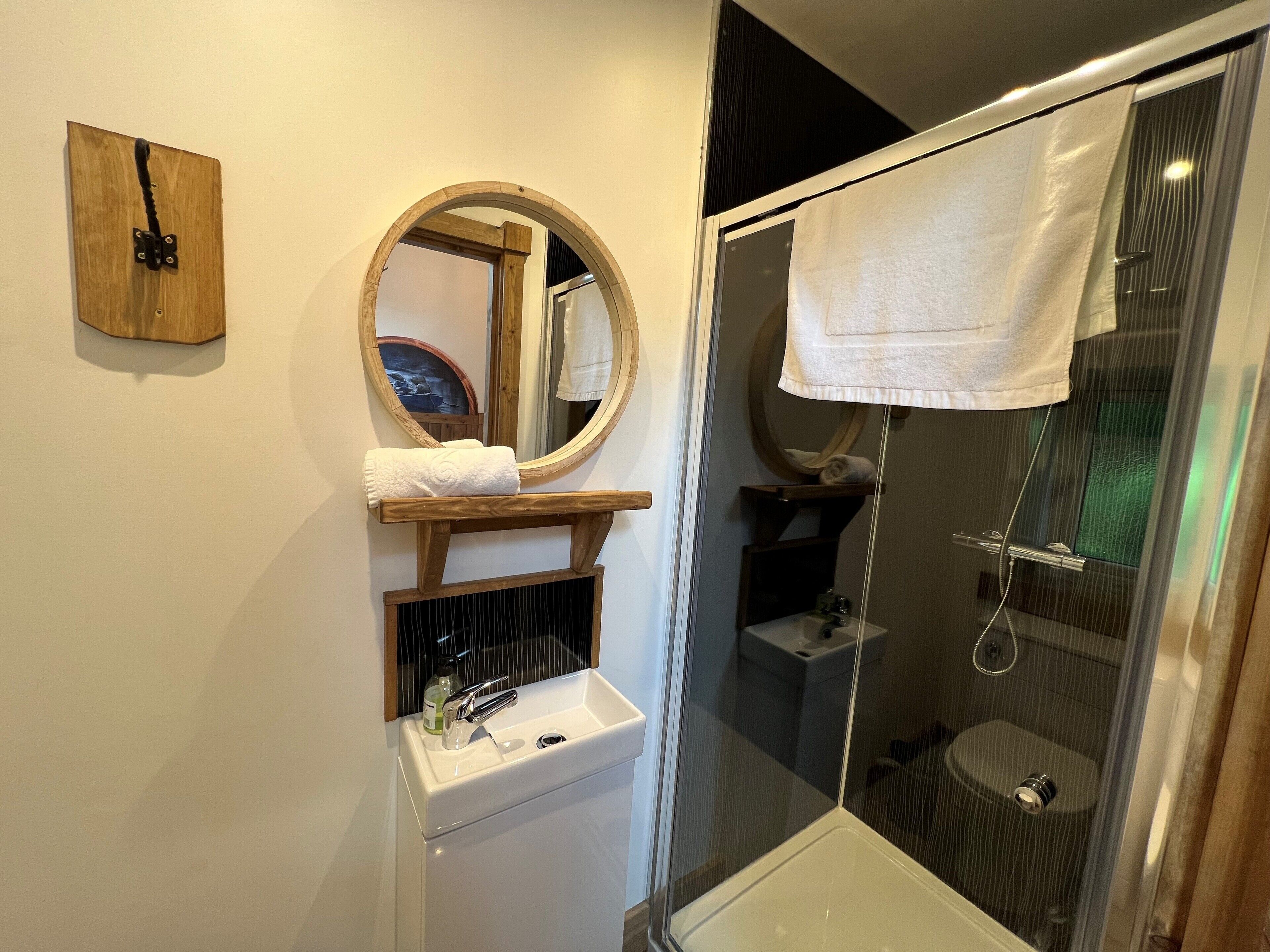 A bathroom with a sink, mirror, towel rack, and shower.