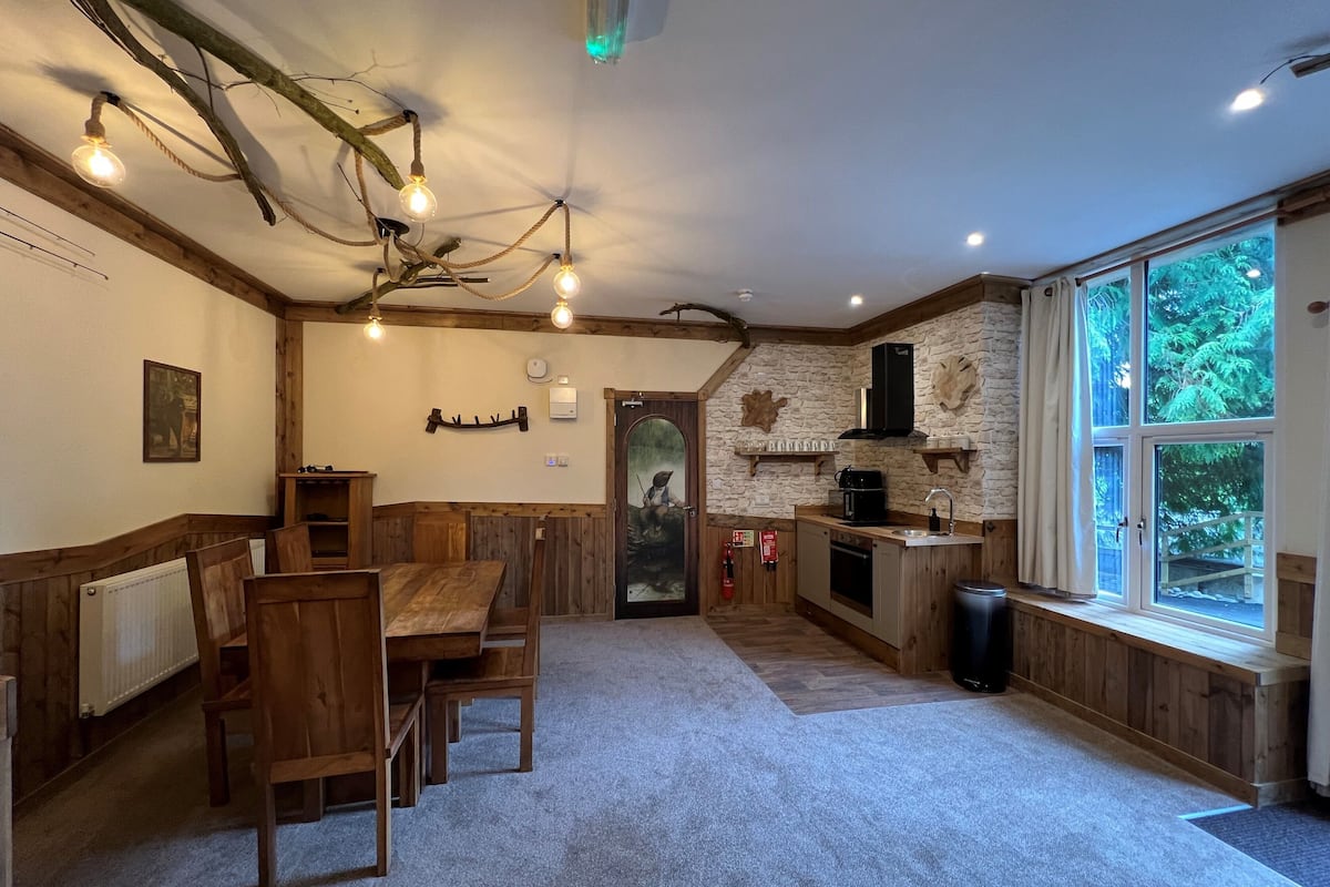 A rustic kitchen with wooden furniture, a stone wall, and a large window.