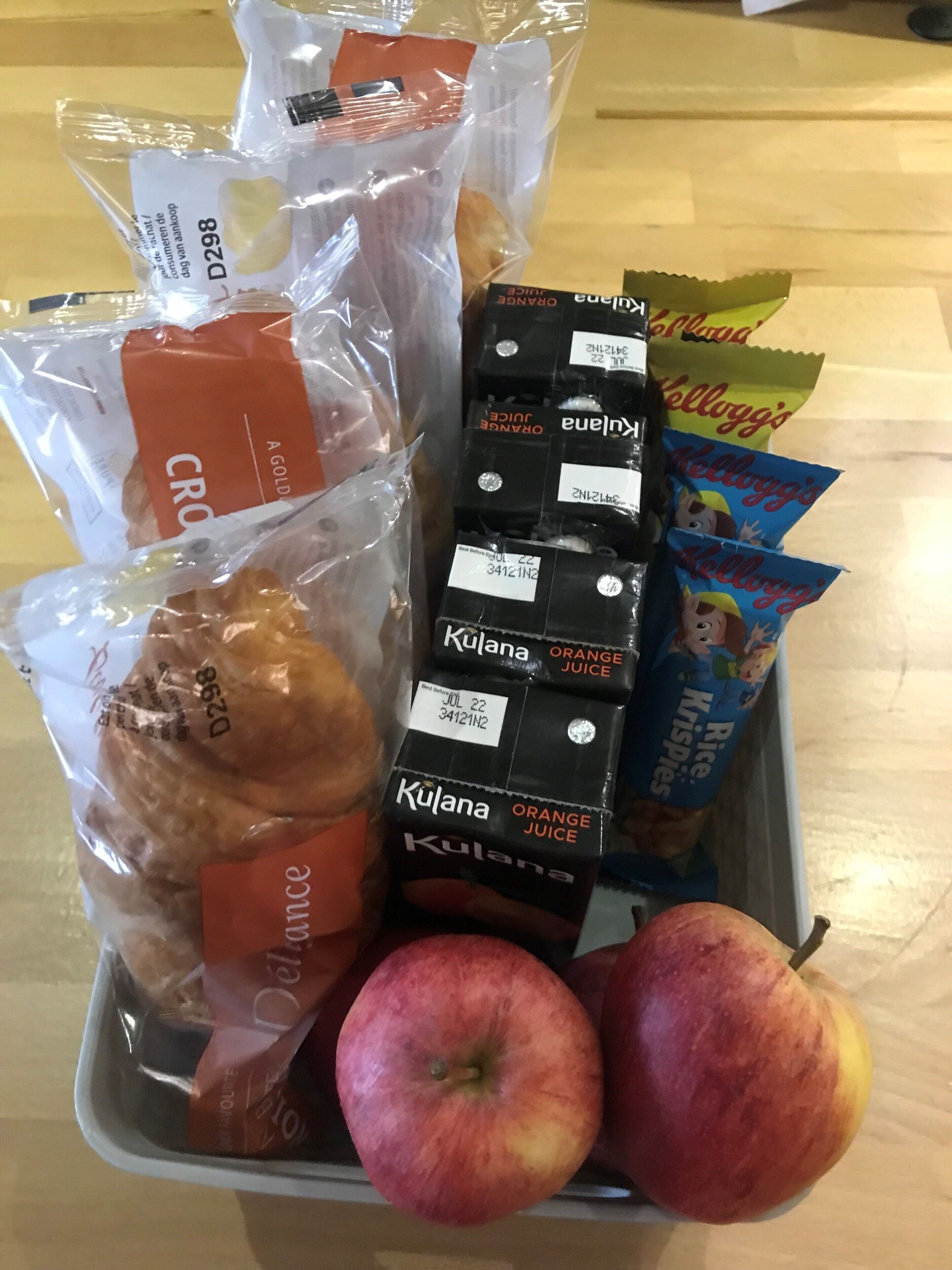 A tray with packaged food items including bread, apples, and various snacks.