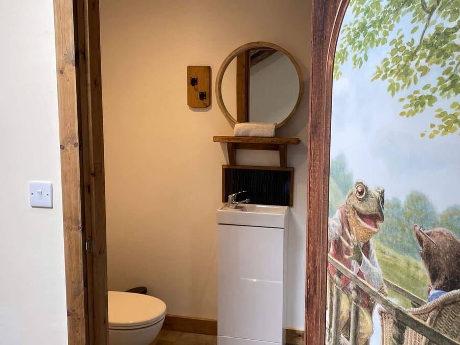 A bathroom with a wooden frame, a white toilet, a sink with a mirror, and a wall-mounted light switch.