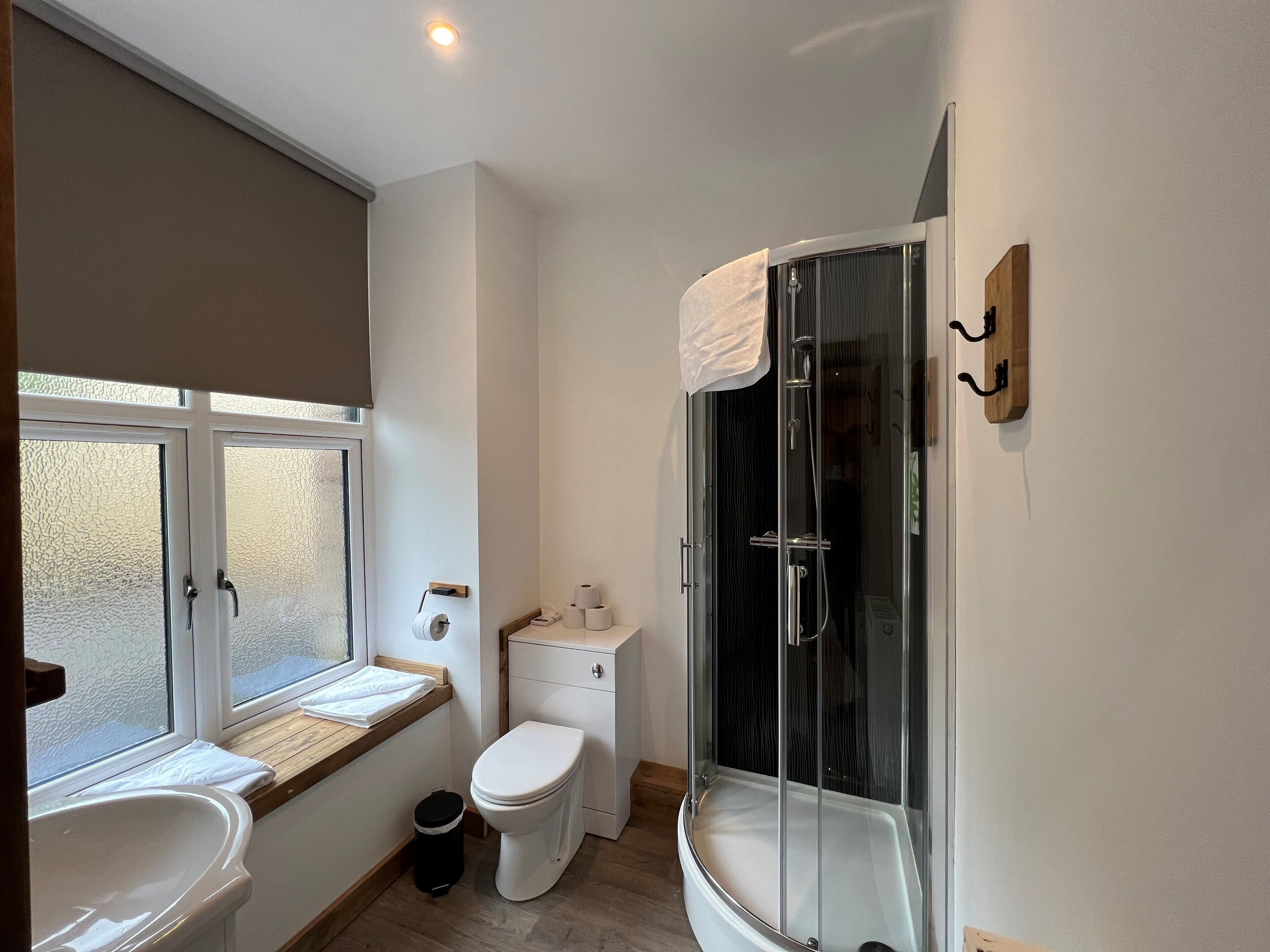 Une salle de bain comprenant des toilettes, un lavabo et une douche fermée par une paroi de verre.