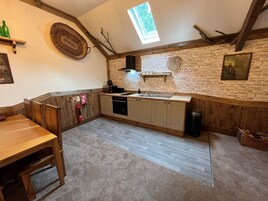 Una cocina acogedora con armarios de madera, pared de piedra, tragaluz y extintor.