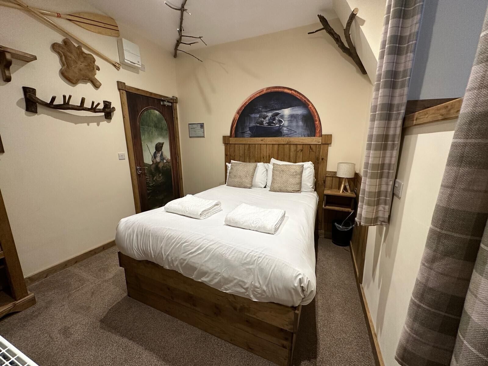Un dormitorio con cama de madera, ropa de cama blanca, un cuadro sobre la cama y cabecera de madera.