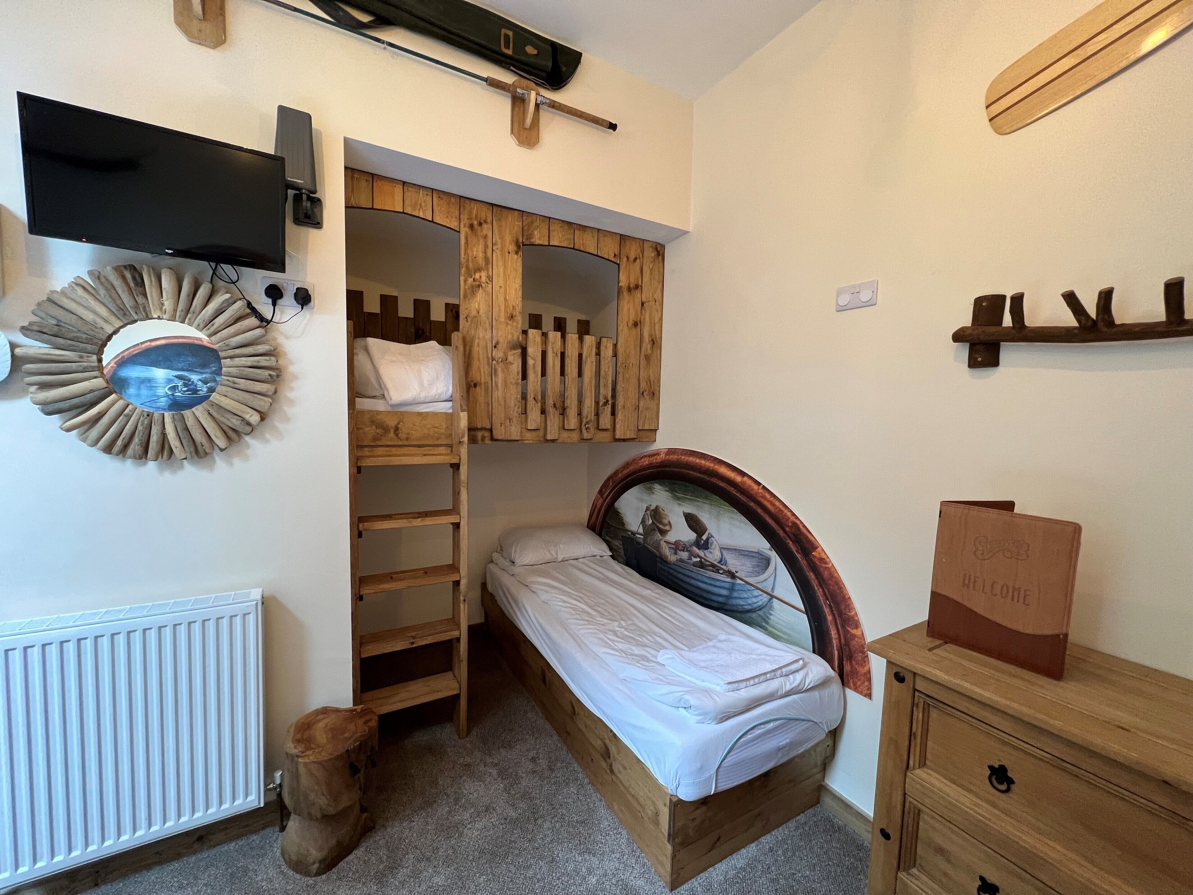 A compact bedroom with a bunk bed, a small desk, and a radiator.