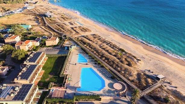 An aerial view of a coastal resort with a swimming pool, beach, and villas. - Pestana Alvor Beach Villas (Portimão)