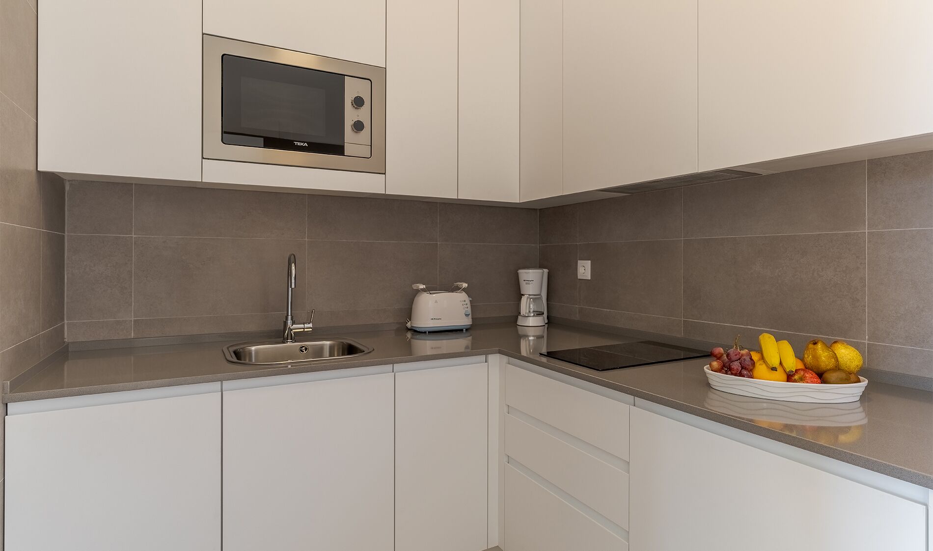 Eine moderne Küche mit eingebauter Mikrowelle, Spüle, Toaster und Kaffeemaschine.