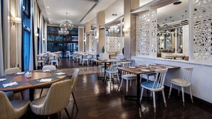 A spacious restaurant with high ceilings, modern chandeliers, and a variety of seating arrangements including tables and chairs. - Pestana Alvor Beach Villas (Portimão)