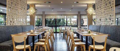 A restaurant with wooden tables and chairs, grey upholstered booths, and decorative wall panels.
