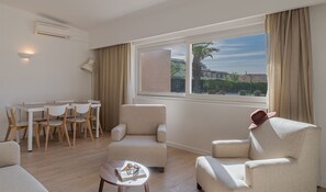 A modern living room with a dining area, a sofa, and a coffee table. - Pestana Alvor Beach Villas (Portimão)