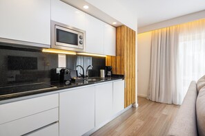 A modern kitchen with white cabinets, a black countertop, and a built-in microwave. - Pestana Alvor Beach Villas (Portimão)