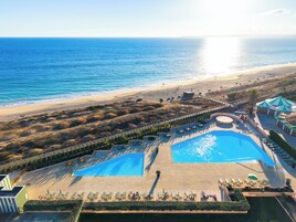 Un resort con una piscina grande, acceso a la playa y vistas al océano.