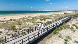 A wooden boardwalk along a beach with a clear view of the ocean and sandy dunes. - Pestana Alvor Beach Villas (Portimão)