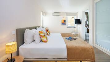 Habitación de hotel con cama, lámpara de noche, televisor de pantalla plana y ventana con vistas.