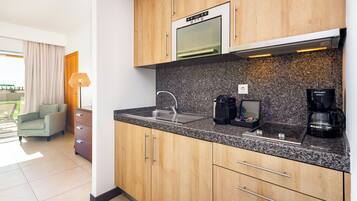 Una cocina moderna con gabinetes de madera, horno integrado, cafetera y lavabo.
