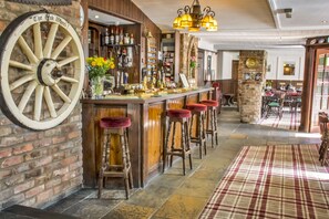 A bar area with a large wooden wheel, bar stools, and a variety of bottles and glasses on shelves. - The Oak Wheel Pub (Scarborough)