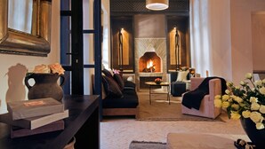 A cozy living room with a fireplace, a sofa, a coffee table, and a bookshelf. - Maison Manzano  (Marrakech)