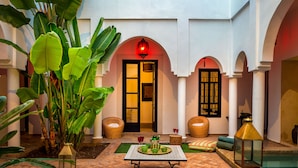 An indoor courtyard with a tiled floor, a table with green bowls, wicker chairs, and a lantern. - Maison Manzano  (Marrakech)