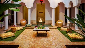 A courtyard with a table, cushions, and a lantern. - Maison Manzano  (Marrakech)